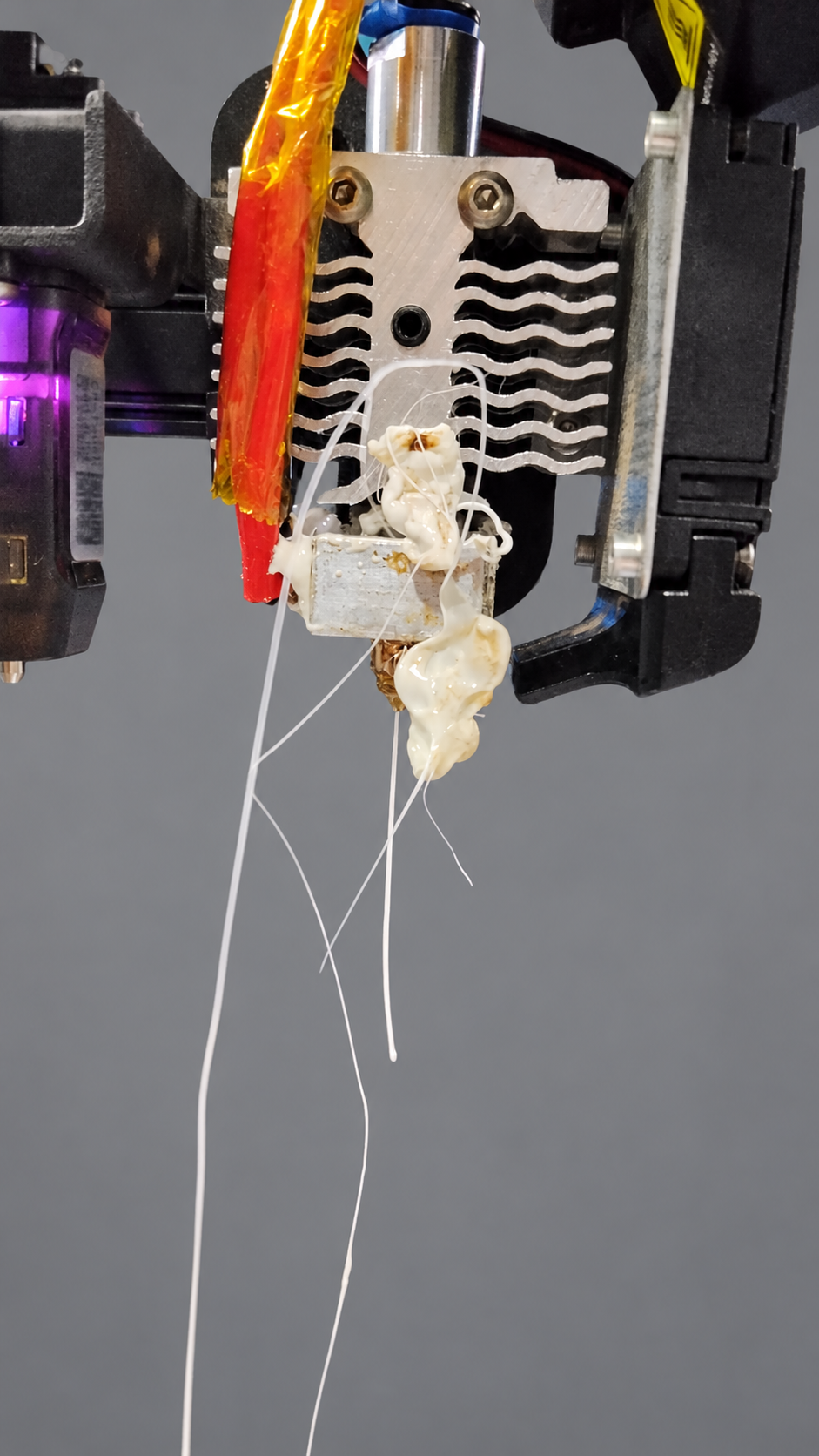 Hotend da Ender-3 V2 Neo exposto, com filamento branco acumulado junto ao bloco aquecedor