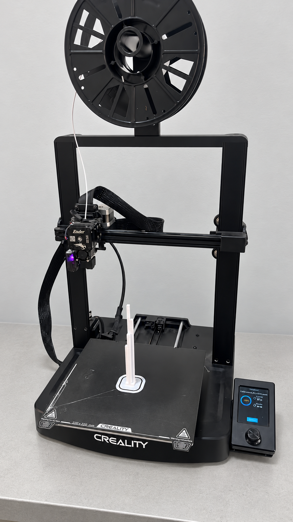 Creality Ender 3 V3 SE em bancada com cabeçote exposto, sensor iluminado e peça branca sobre a mesa