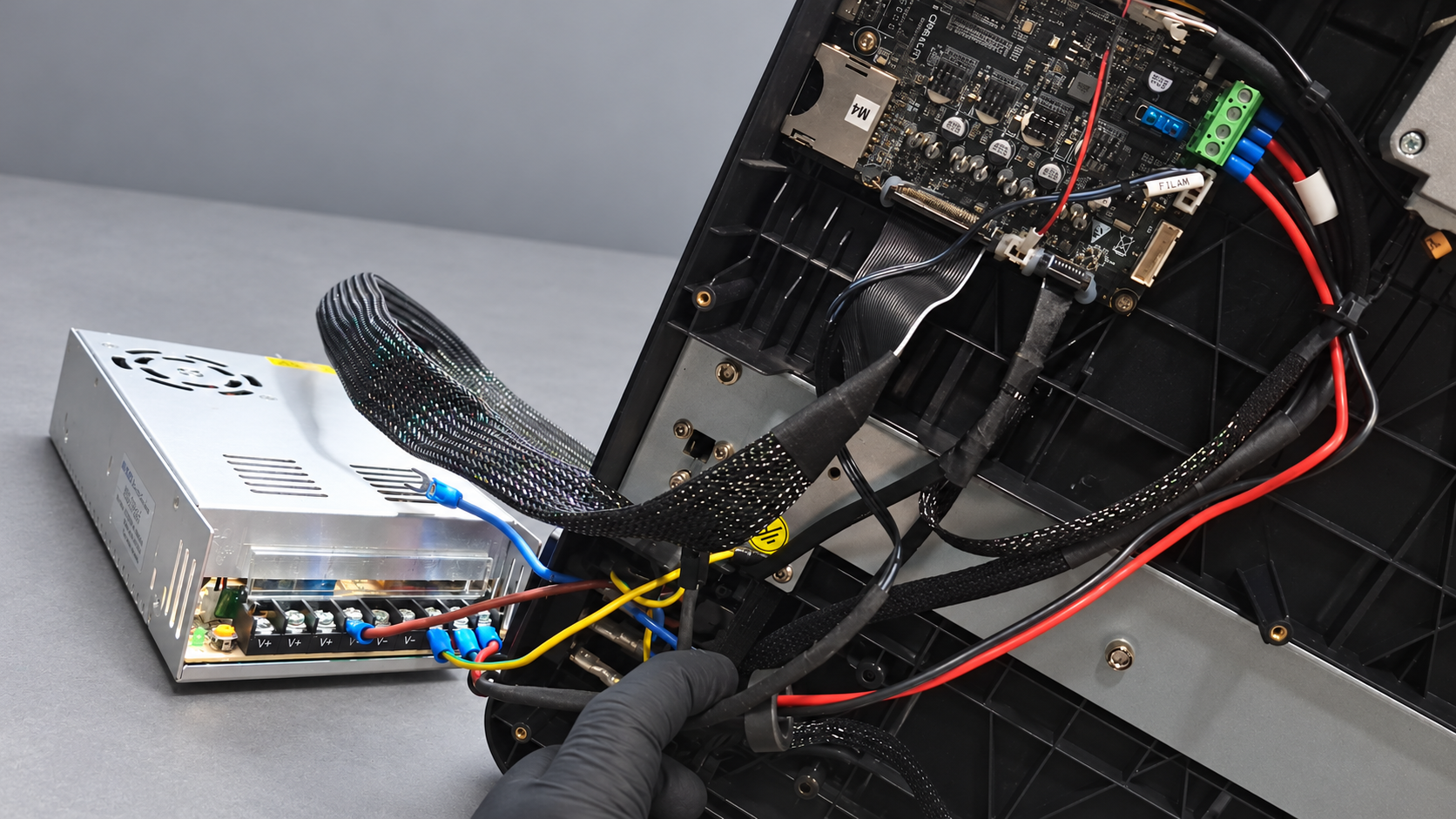 Base aberta da Ender 3 V3 SE, com placa eletrônica, cabos e fonte externa